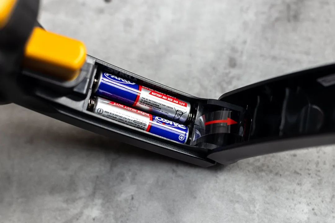 The inside of the Etekcity Lasergrip 1080’s battery compartment, with two triple-A batteries and a pull tab.