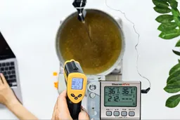 The Etekcity Lasergrip 1080 measures the surface temperature of a pan of cooking oil from 16 inches away. The screen reads 381.2F.