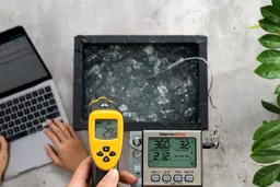 The Etekcity Lasergrip 800 is being used by a reviewer to measure the surface temperature of an ice bath from a distance of 16 inches. The screen displays 29°F.