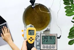 A reviewer is using the Etekcity Lasergrip 800 to measure the surface temperature of a vat of hot oil at a distance of 16 inches. The screen reads 367.4°F.