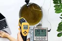 A reviewer is using the Etekcity Lasergrip 800 to measure the surface temperature of a vat of hot cooking oil from a distance of 12 inches. The screen reads 369.4°F.