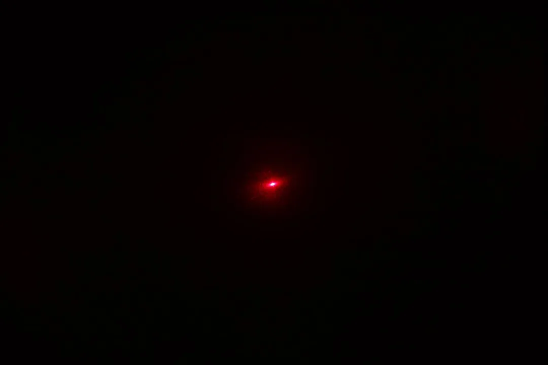 The red dot of the Eventek ET312’s laser emitter in a dark room.