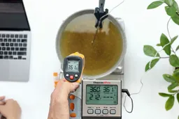 The Helect IR thermometer measures the temperature of boiling oil from 16 inches away. The screen shows 361.6°F.