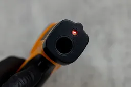 A close-up view of the laser emitter and the sensor head of the Helect IR thermometer.