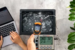 A reviewer is using the Kizen LaserPro LP300 at a distance of 16 inches to measure the surface temperature of an ice bath. The screen reads 31.3°F.