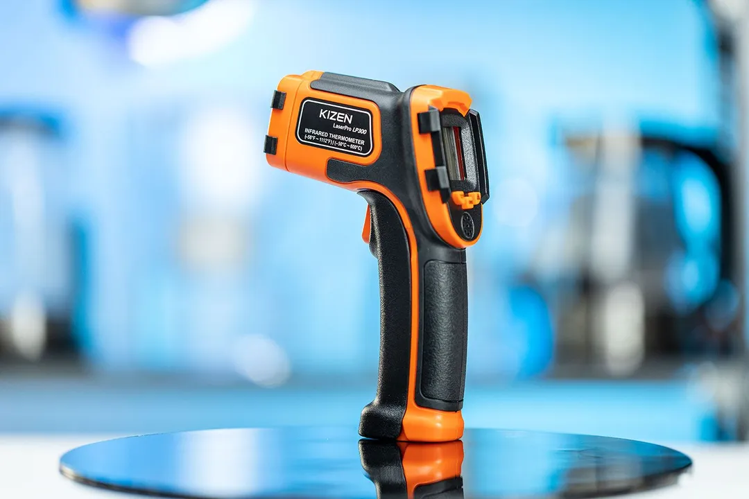 The Kizen LaserPro LP300 Infrared Thermometer Gun standing upright on its handle on a turn table against a blurry blue backdrop.