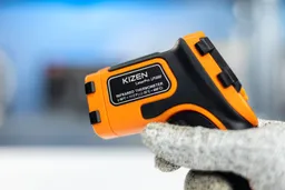 The Kizen LaserPro LP300 IR thermometer in the white-gloved hand of a reviewer.
