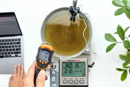 A reviewer is using the Kizen LaserPro LP300 at a distance of 12 inches to measure the surface temperature of a pan of hot oil. The screen reads 378°F.