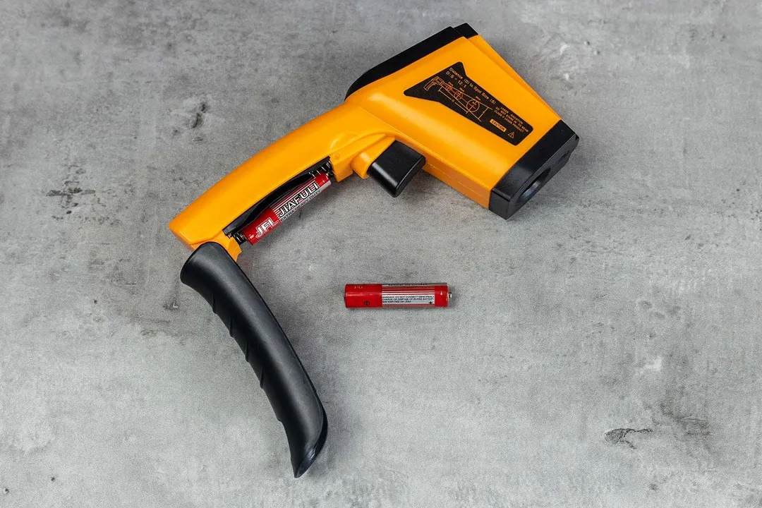 The Lasergrip GM400 with its battery compartment opened. To its right is one AAA battery.