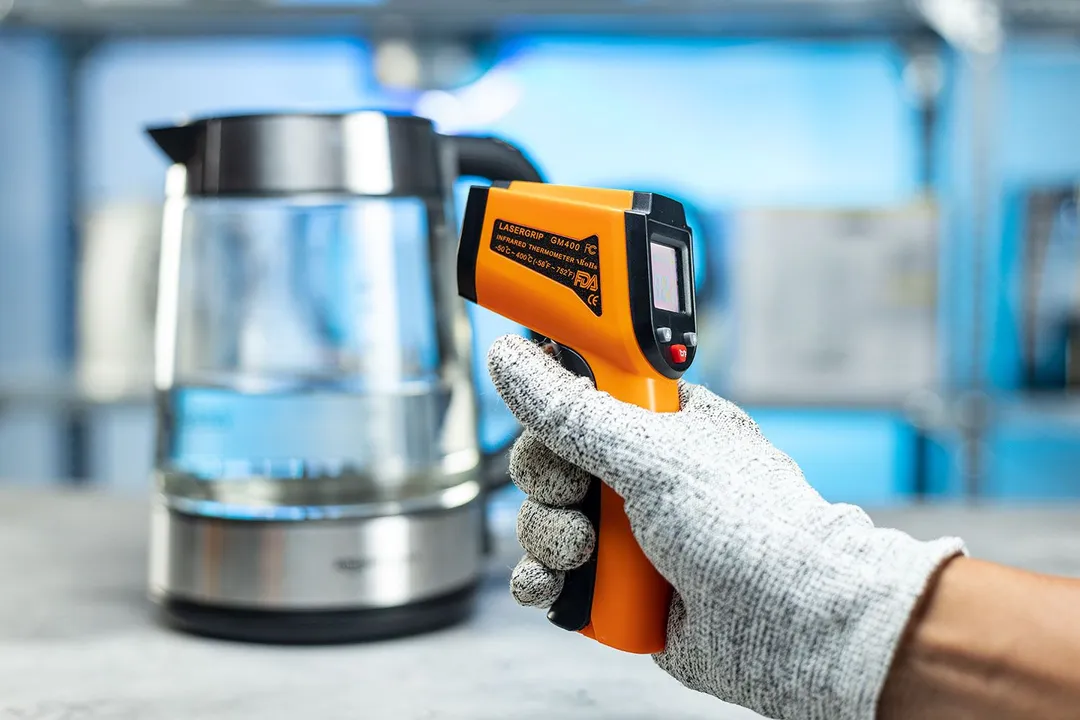The Lasergrip GM400 Infrared Thermometer standing upright on its handle on a turn table against a blurry blue backdrop.