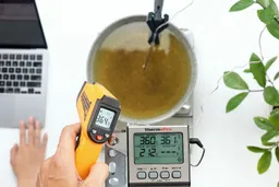 The Lasergrip GM400 measures the surface temperature of a pan of cooking oil from 16 inches away. The screen reads 364.4°F.