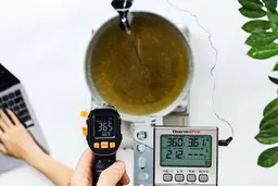 The Mecurate IRT600A is used to scan the temperature of boiling oil in a pan from 16 inches away. The screen reads 365°F.