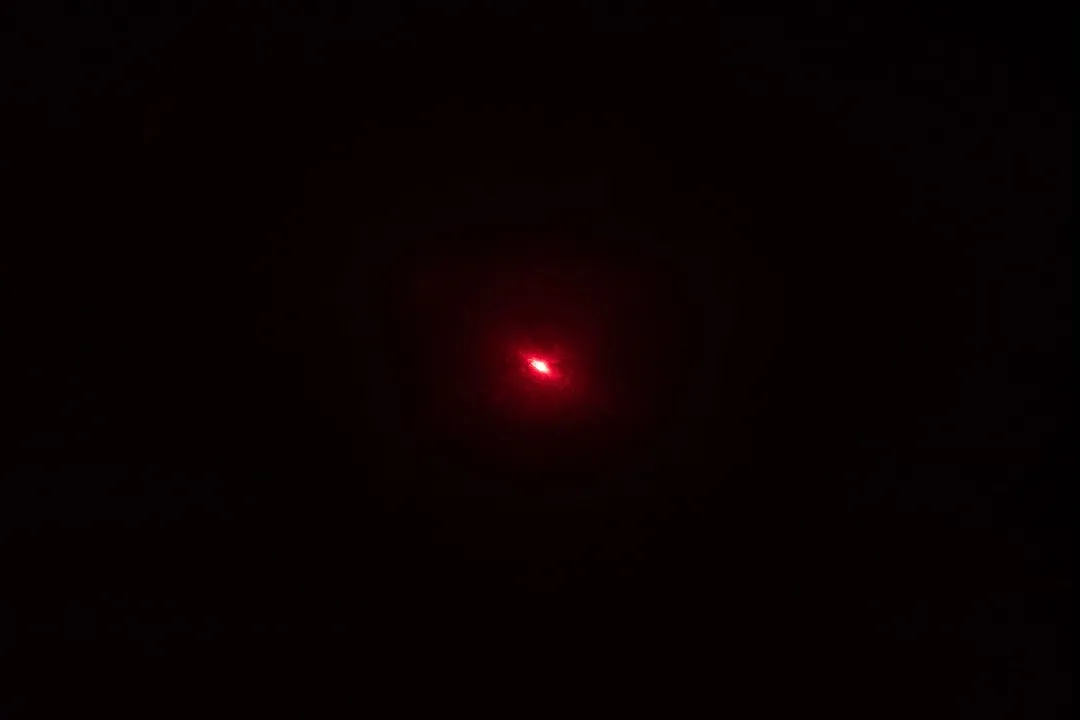 The red laser dot of the Smart Sensor AS530 IR thermometer’s laser emitter in a dark room.