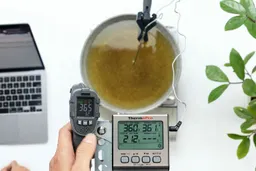 The Sovarcate HS980E IR thermometer measuring the temperature of cooking oil from 12 inches. The screen reads 36.5°F.
