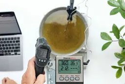 The Sovarcate HS980E IR thermometer measuring the temperature of cooking oil from 16 inches. The screen reads 37°F.