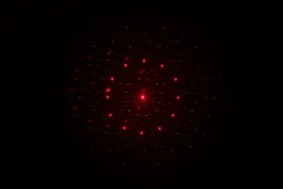 The 13-dot laser pattern of the Sovarcate HS980E on the wall of a dark room.