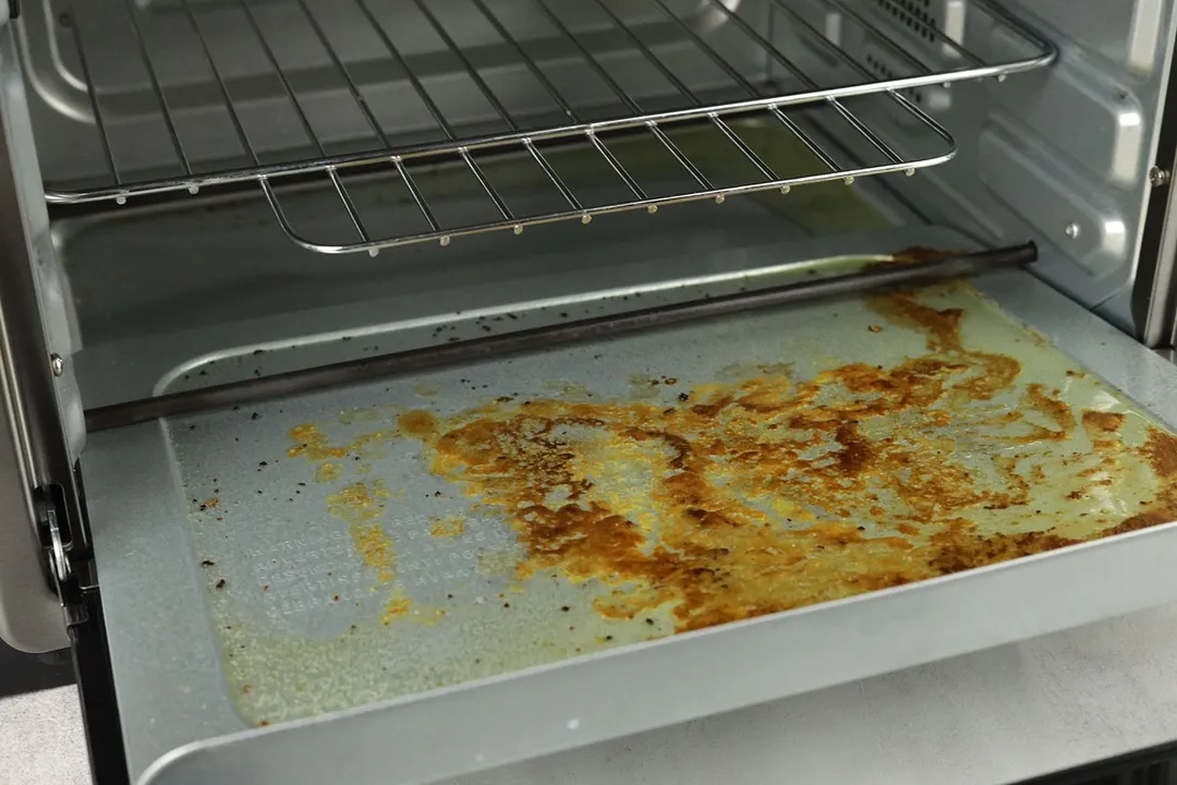 Grease on the removable crumb tray inside the cooking chamber of the Toshiba AC25CEW-BS Convection Toaster Oven.