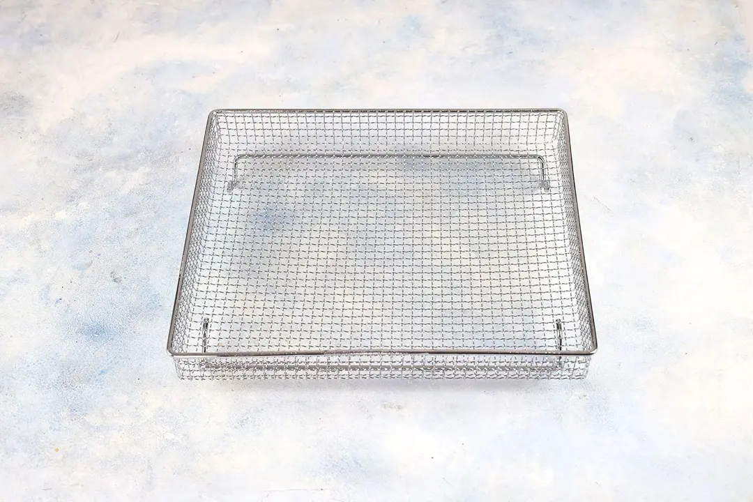 A stainless steel air fryer basket of the Cuisinart TOA-60 Convection Toaster Oven Air Fryer on a white background.