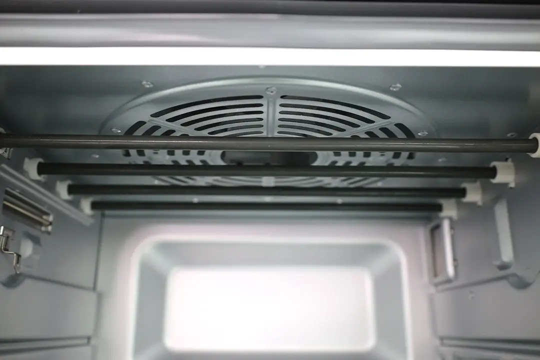 The cooking chamber ceiling of the Cuisinart TOA-60 Toaster Oven has a convection fan cavity and four nichrome heating elements. The cooking chamber also has a safety hook on the left and interior light on the right.