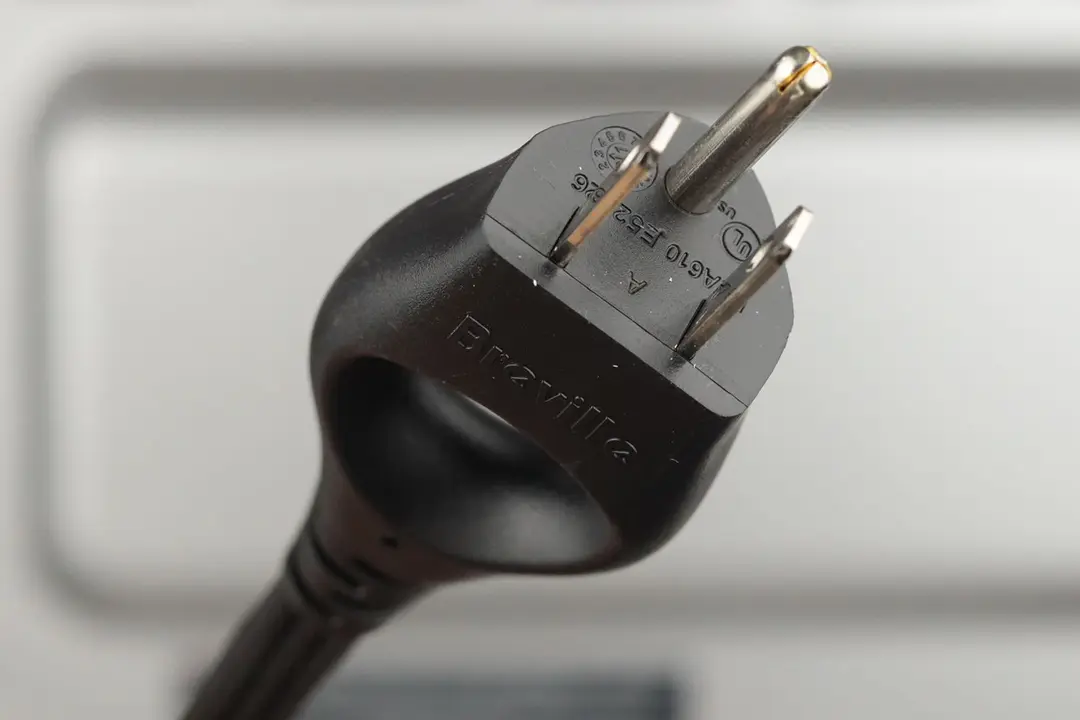 A three-pronged plug power cord. In the background is the stainless steel Breville BOV450XL Mini Smart Toaster Oven.