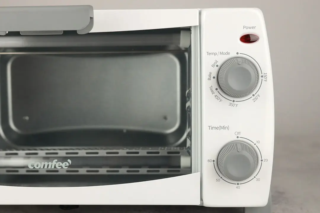 The control panel of the Comfee CFO-BB101 Toaster Oven has a control dial for temperature/mode above and one for timer below.