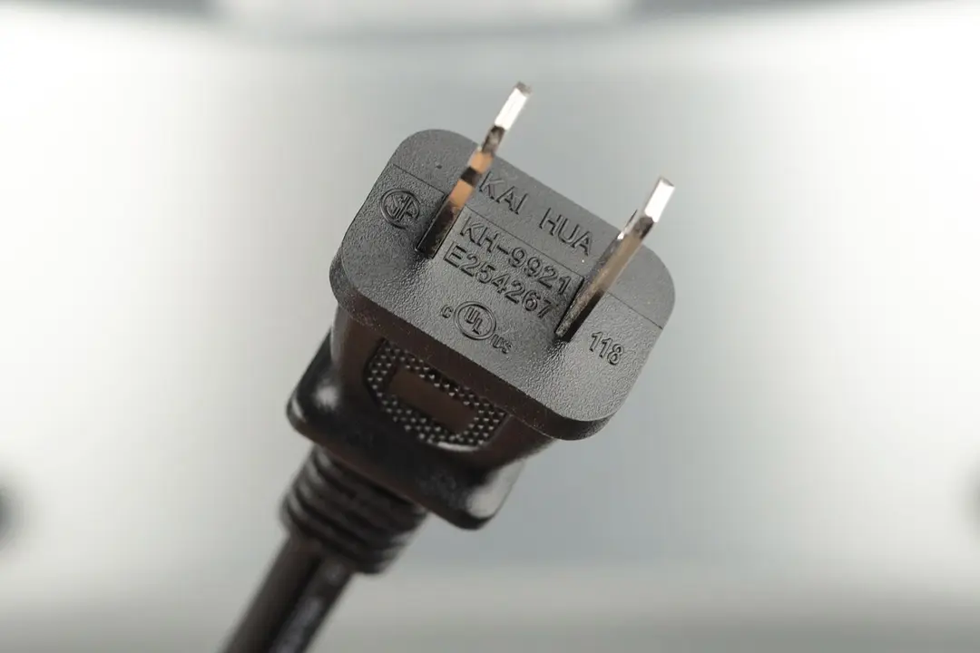 A two-pronged plug power cord. In the background is the white Comfee CFO-BB101 Compact Countertop Toaster Oven.