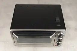 On a grey background, the top of the stainless steel Cuisinart TOB-40N Custom Classic Toaster Oven Broiler has holes.