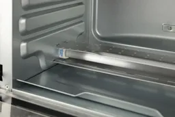 The bottom quartz heating element with guard and 2 rails on the left wall of the Hamilton Beach 31401’s cooking chamber.