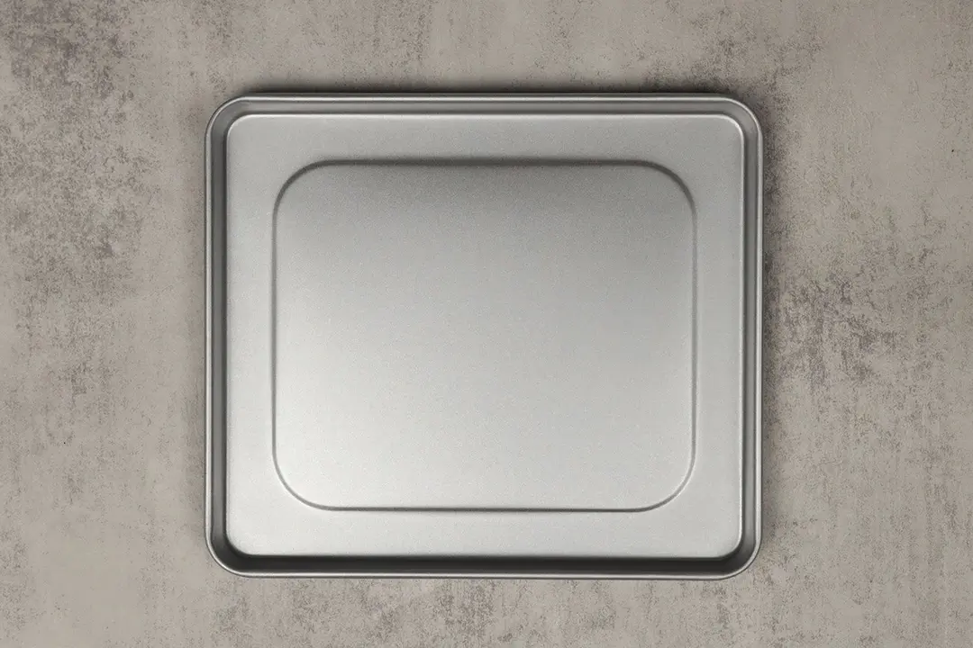 A silver baking pan of the stainless steel Hamilton Beach 31401 4-Slice Countertop Toaster Oven on a grey background.
