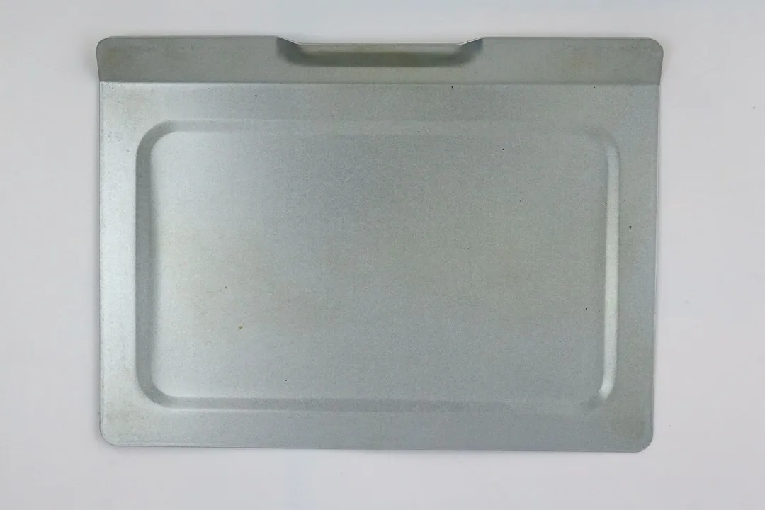 A removable crumb tray of the stainless steel Hamilton Beach 31401 4-Slice Countertop Toaster Oven on a grey background.