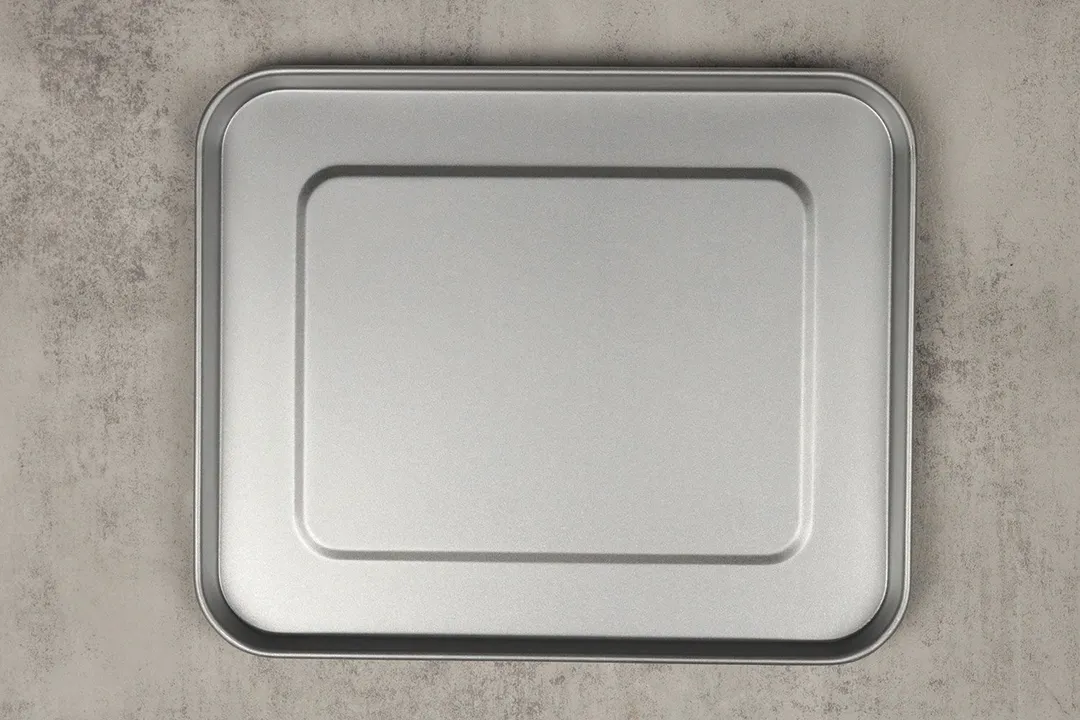 A silver baking pan of the stainless steel Hamilton Beach 31127D 6-Slice Easy Reach Toaster Oven on a grey background.
