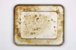 Caramelized meat juice and grease on the silver baking pan of the Hamilton Beach 31127D 6-Slice Easy Reach Toaster Oven.