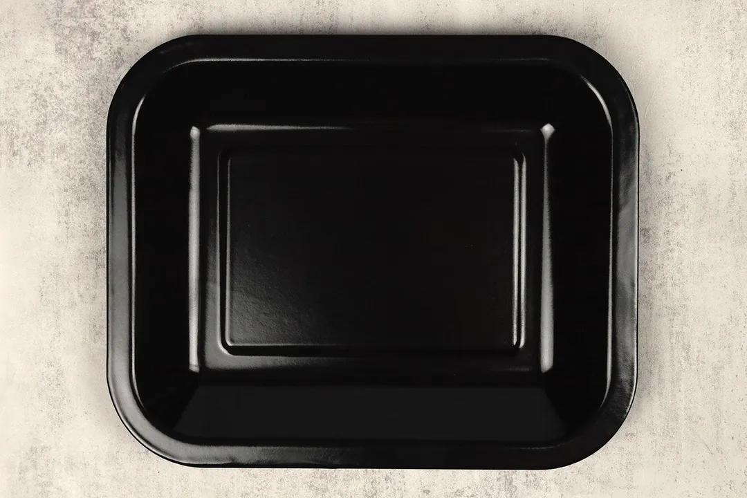 A enamel baking pan of the Oster TSSTTVMNDG-SHP-2 Large Capacity Digital Convection Toaster Oven on a grey background.