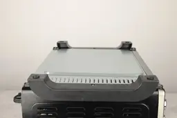 On a grey background, the bottom of the Toshiba AC25CEW-BS Toaster Oven has two black stands and air ventilation holes.