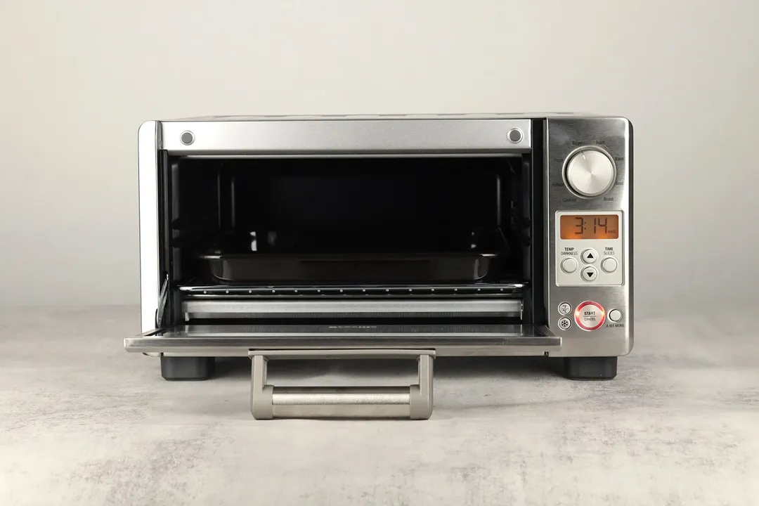 The front of an opened stainless steel Breville BOV450XL Mini Smart Toaster Oven with a baking rack and a baking pan.