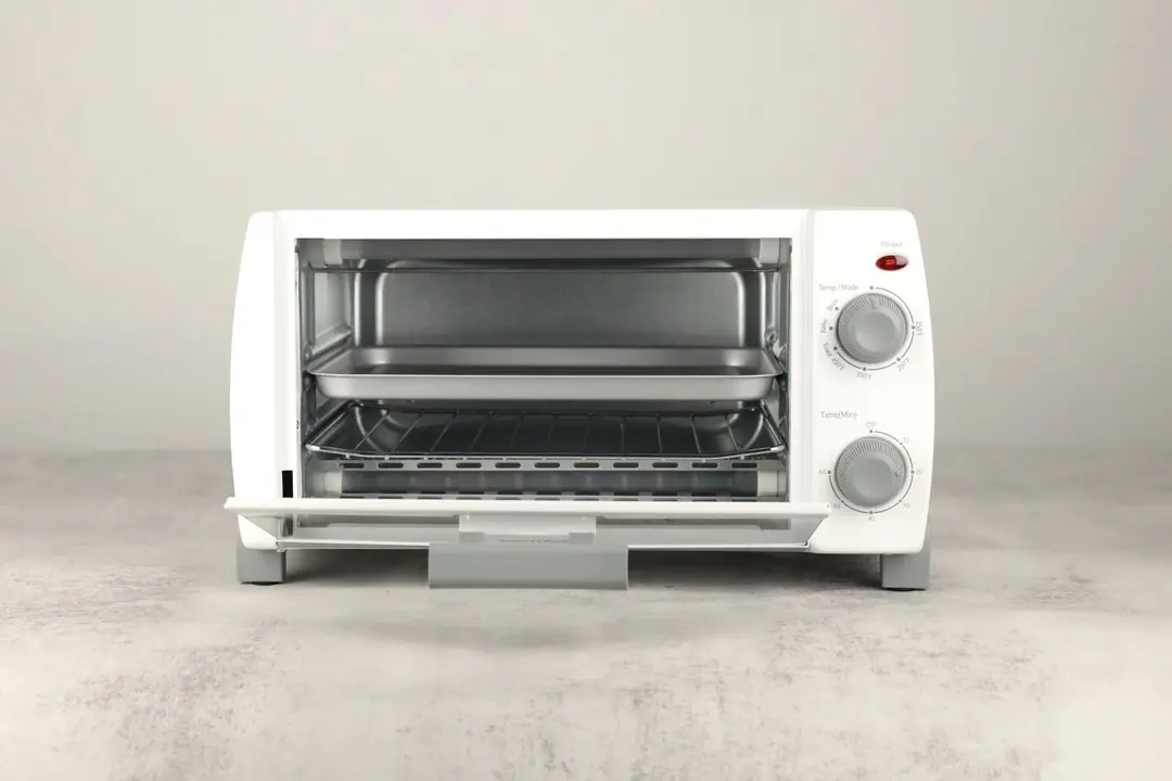 The front of an opened white Comfee CFO-BB101 Compact Toaster Oven with an oven rack and a grooved silver baking pan.