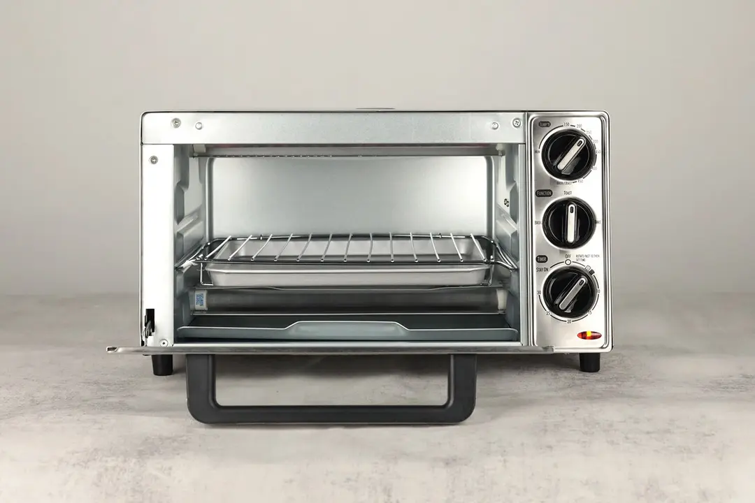 The front of an opened Hamilton Beach 31401 4-Slice Toaster Oven with a silver baking pan and a stainless steel oven rack.