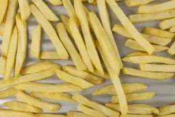 A closeup of pieces of golden baked french fries using a toaster oven on a grooved silver baking pan.