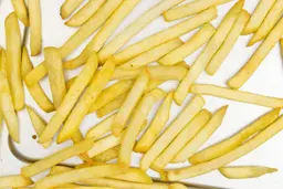 A close-up of pieces of baked french fries using a toaster oven on a silver baking pan.