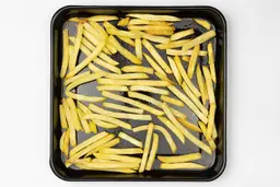 Pieces of baked french fries using a toaster oven on an enamel baking pan on a white background.
