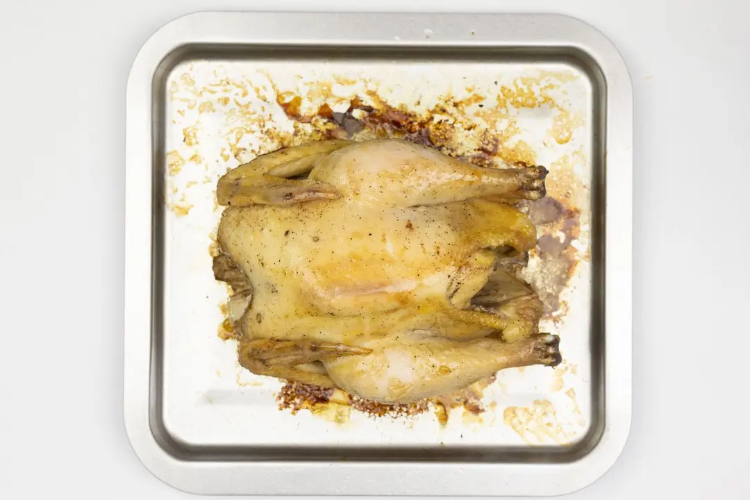 A whole roasted chicken using the Cuisinart TOB-40N Custom Classic Toaster Oven on a silver baking pan on a white background.