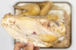 The pink spots near the bone of the chicken. In the white background is the rest of the roasted chicken on a baking pan.