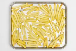 Pieces of baked french fries using the Hamilton Beach 31127D Toaster Oven on a silver baking pan on a white background.