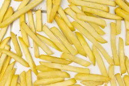 A close-up of pieces of baked french fries using the Hamilton Beach 31127D 6-Slice Toaster Oven on a silver baking pan.