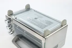 On a white background, the bottom of the Black+Decker TO1760SS Natural Convection Toaster Oven has four stands and holes.