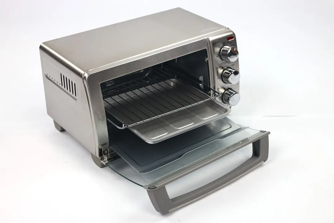 The front of an opened Black+Decker TO1760SS 4-Slice Toaster Oven with a removable crumb tray, baking pan, and oven rack.
