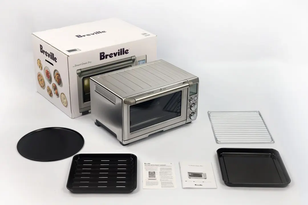 A box, the Breville BOV845BSSUSC, a pizza pan, a broiling rack, a warranty, a user manual, an oven rack, and a baking pan.
