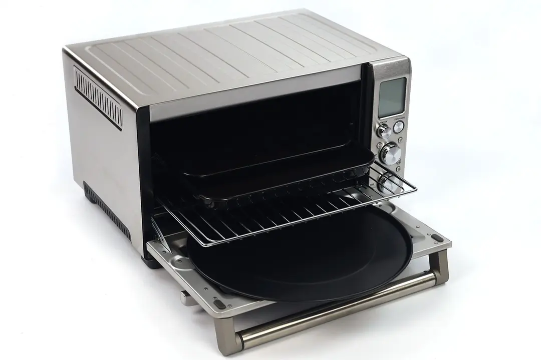 The front of an opened Breville BOV845BSSUSC Toaster Oven with a pizza pan, oven rack, enamel baking pan, and broiling rack.