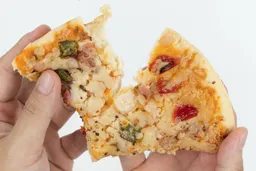 Two hands break apart a slice of pizza with cheese, meat, onions, and green bell peppers on top baked using a toaster oven.