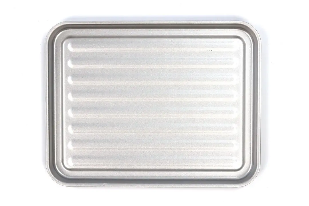A grooved silver baking pan of the stainless steel Mueller MT-175 4-Slice Countertop Toaster Oven on a white background.